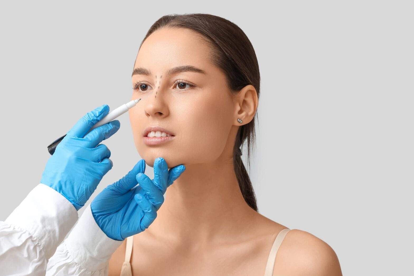 patient getting facial injections by hands in blue gloves.